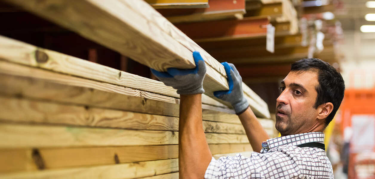 Man working at home improvement place carrying lumber