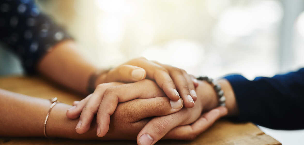 Couple holding hands while resting them on a table
