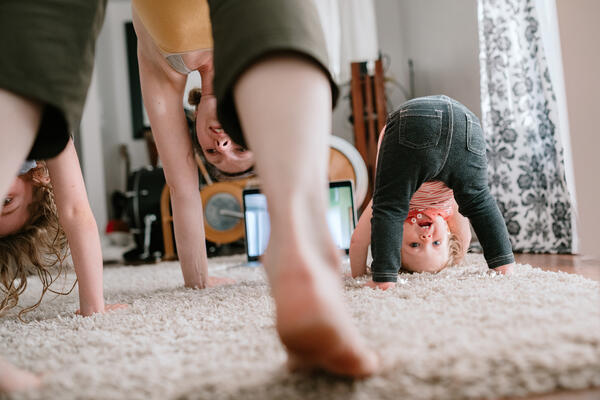 Mother and children doing downward dogs in the living room