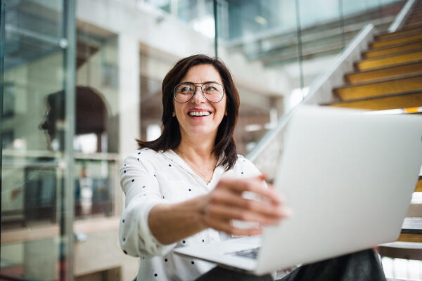 Woman smiling while showing her laptop to others