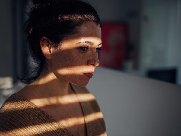 Woman looking through window blinds