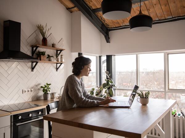 Woman working in kitchen on laptop