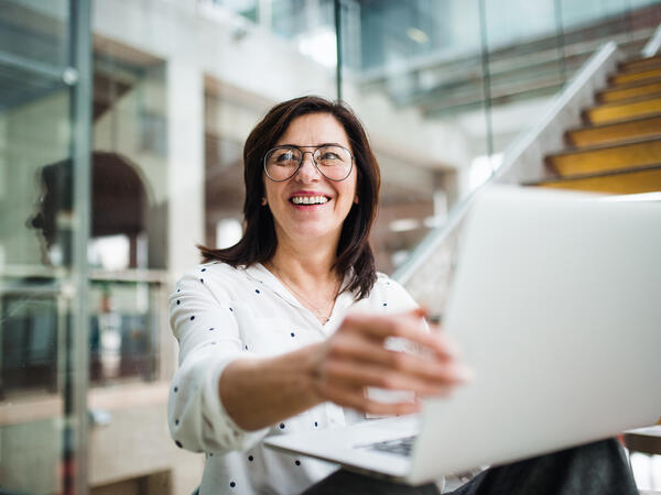 Femme souriante, montrant l’écran de son ordinateur portable à d’autres personnes