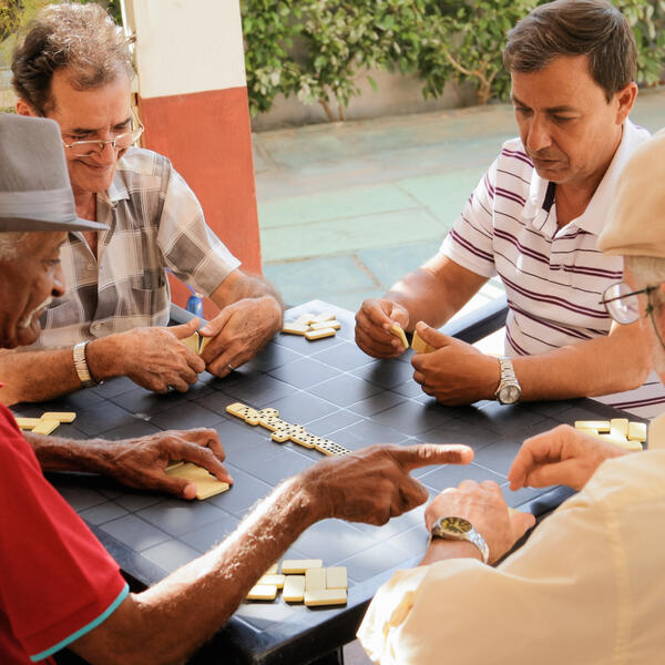 Old men playing dominos around table